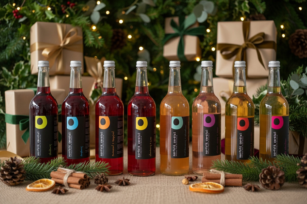 Row of eight bottles with different colored liquids on a wooden surface against a white paneled wall.