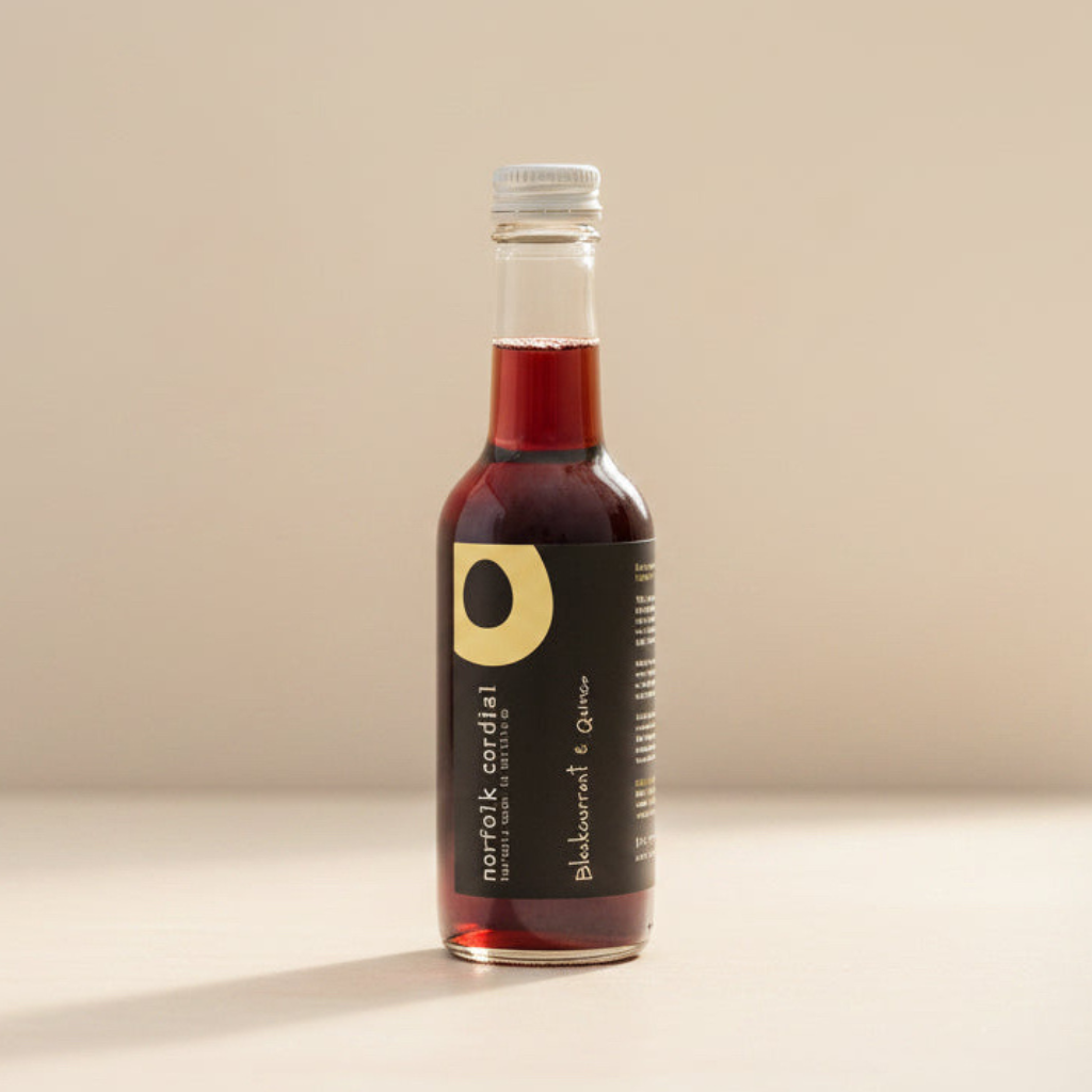 Norfolk Cordial Blackcurrant & Quince 250ml bottle on a warm neutral background