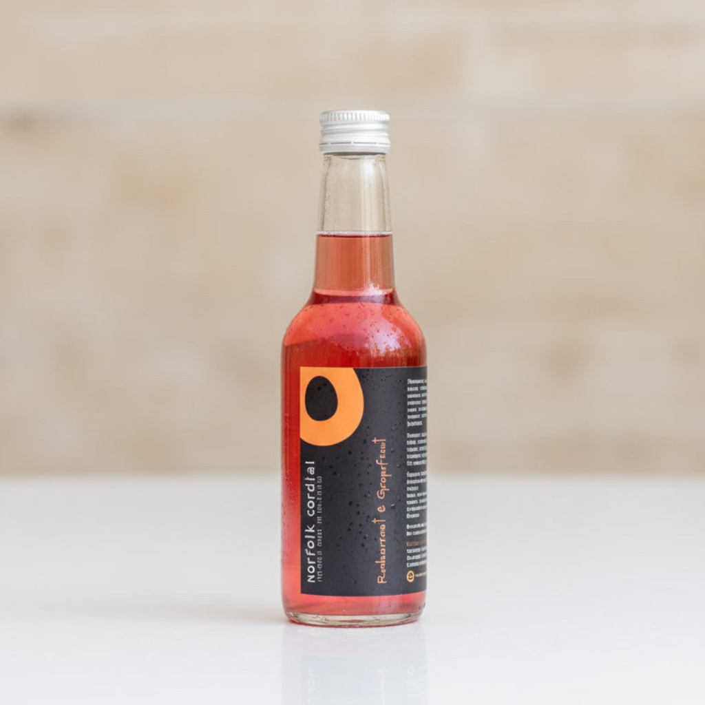 Norfolk Cordial Redcurrant & Grapefruit 250ml bottle on a warm neutral background