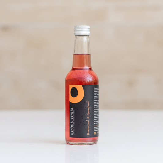 Norfolk Cordial Redcurrant & Grapefruit 250ml bottle on a warm neutral background